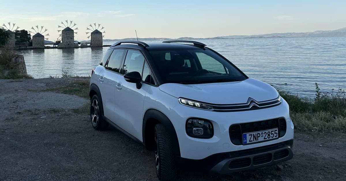 A rental car on a coastal road in Chios with the windmills in the background